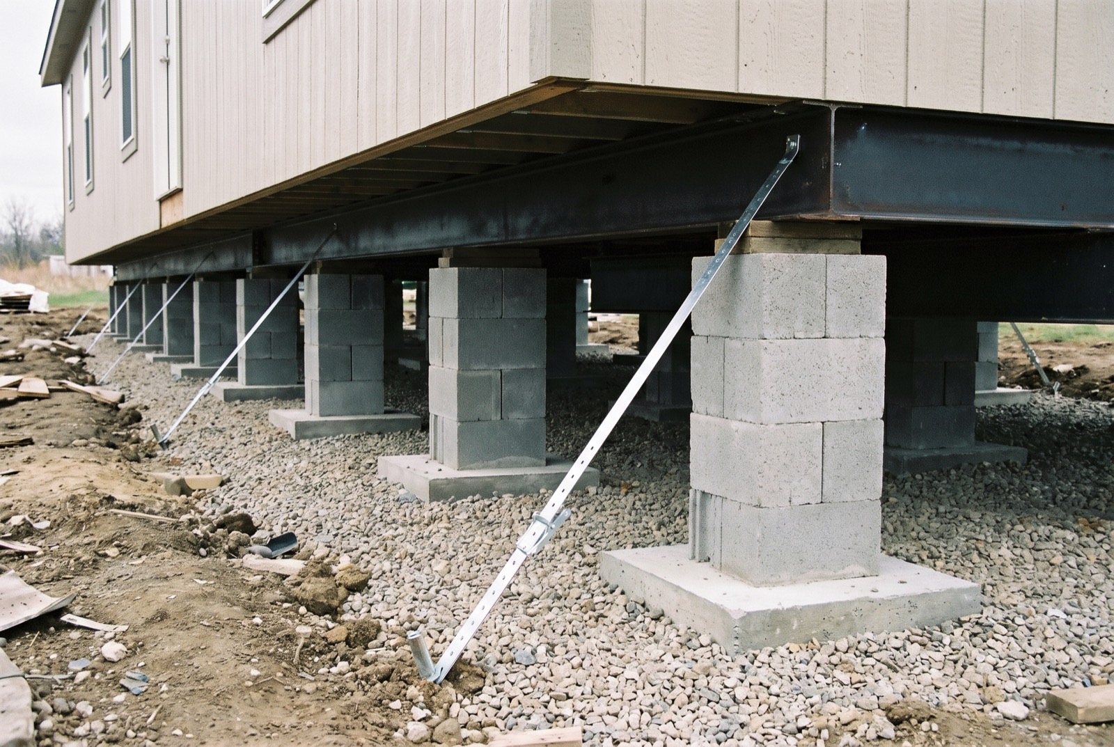 New block piers, footings, and anchor straps under a manufactured home
